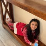 Long custom wood farmhouse table with elf. Young girl lying on the bottom of table.